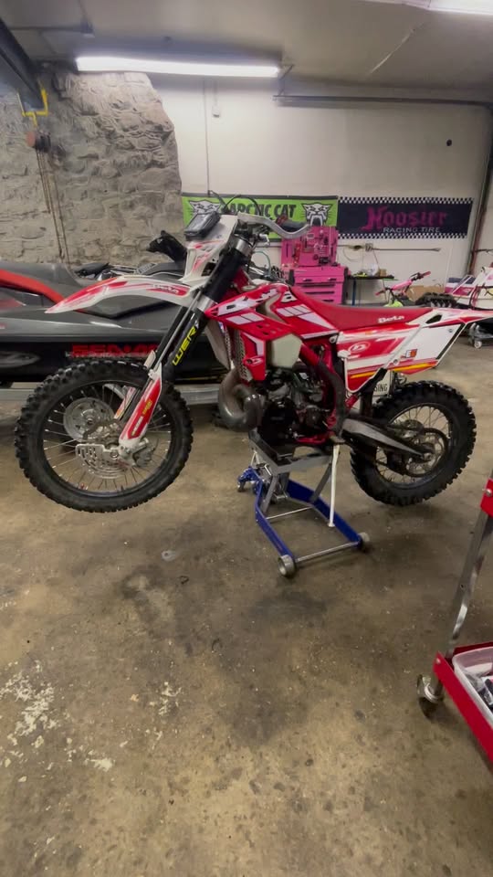 Red and white dirt bike on a work stand inside the Lake Hopatcong Motorsports shop